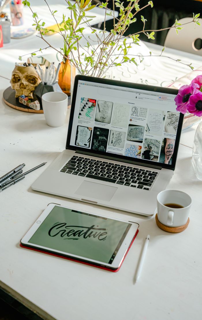 A well-organized workspace featuring a laptop, tablet, and calligraphy tools, ideal for creative projects.